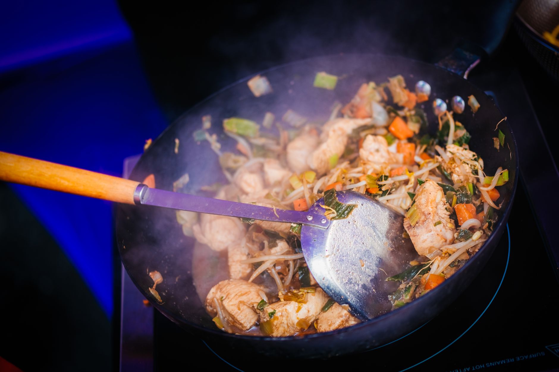 Sizzling chicken stir fry with vegetables cooked in a wok on stovetop, ideal for healthy eating.